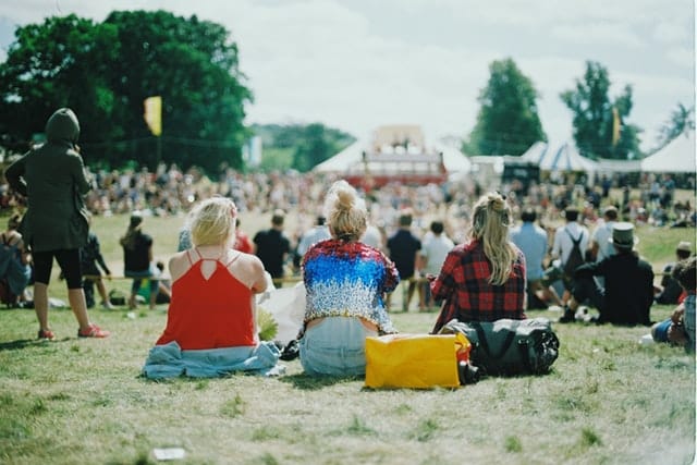 jovenes sentadas viendo un concierto en un festival