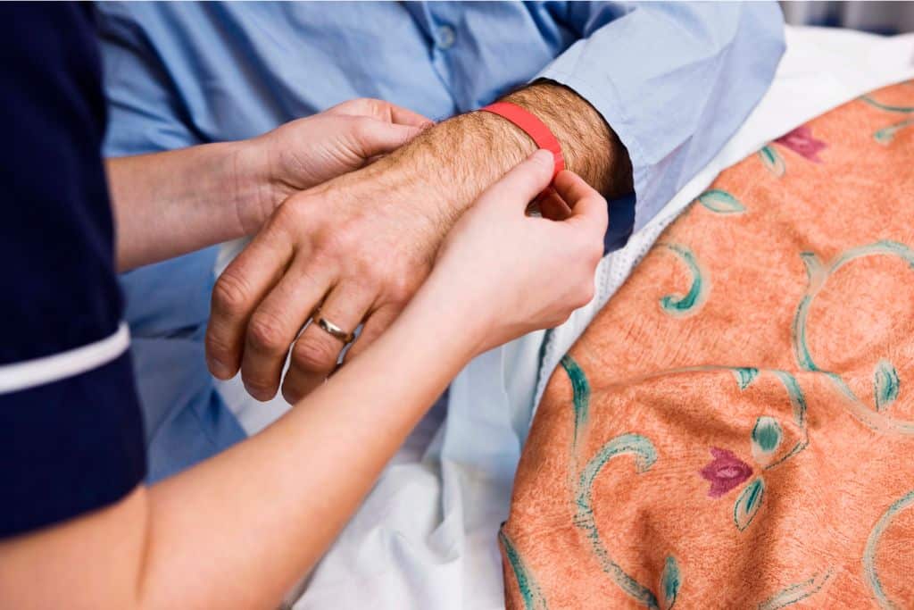 La foto muestra a una enfermera utilizando una pulsera de silicona para identificar a un paciente en un hospital